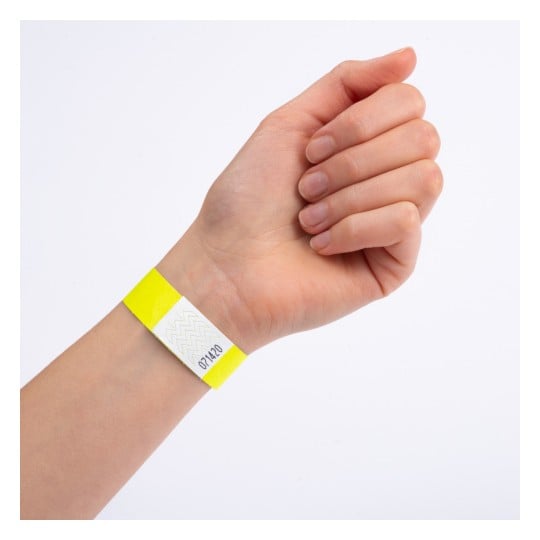 Eine Hand mit einem gelben Armband, das einen weißen Abschnitt und eine darauf gedruckte Zahl hat.