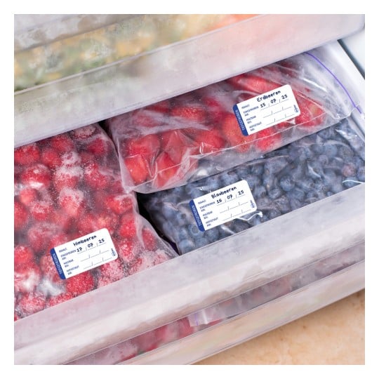 Das Bild zeigt mehrere Packungen gefrorener Beeren, die auf Deutsch etikettiert sind, darunter Erdbeeren und Blaubeeren, die in einem Gefrierschrank gelagert werden.