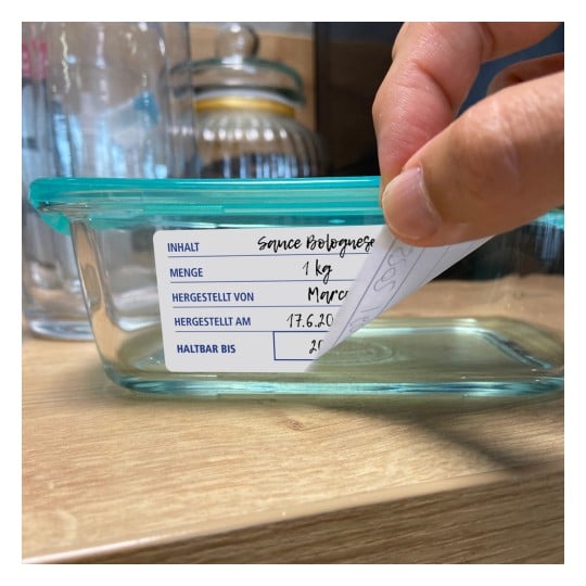 Ein Glasbehälter mit der Aufschrift 'Sauce Bolognese', der Angaben zu den Zutaten, dem Gewicht, dem Hersteller, dem Produktionsdatum und dem Verfallsdatum enthält.