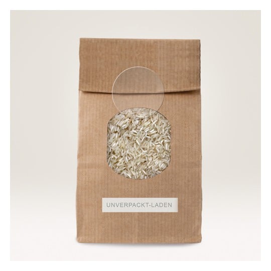 The image shows a brown paper bag with a circular window displaying white rice inside. The bag is labeled 'UNVERPACKT-LADEN.'