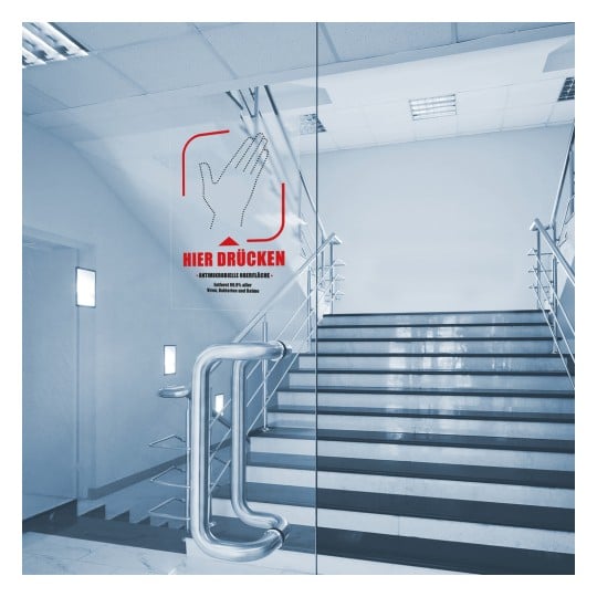 Das Bild zeigt eine Treppe mit einer Glastür neben einem Schild, das die Benutzer anweist zu drücken. Das Schild weist darauf hin, dass es antimikrobielle Oberflächen aufweist und hebt die Sicherheit hervor.