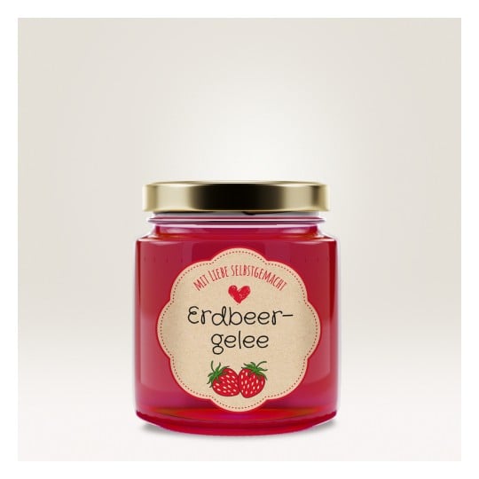 Das Bild zeigt ein Glas mit Erdbeergelee, das ein dekoratives Etikett mit den Worten 'Erdbeergelee' und Abbildungen von Erdbeeren aufweist. Das Glas hat einen goldenen Deckel und eine leuchtend rote Farbe.