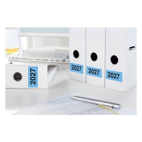 Vier weiße Ordner mit der Aufschrift '2027' auf einem Schreibtisch mit einer Computertastatur.