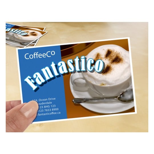 Das Bild zeigt eine Werbekarte eines Cafés, auf der ein Cappuccino mit Schaum und Kakaopulver abgebildet ist. Die Karte enthält den Namen "CoffeeCo" und das Wort "Fantastico" in prominenter Darstellung. Kontaktinformationen und eine Website sind ebenfalls sichtbar.
