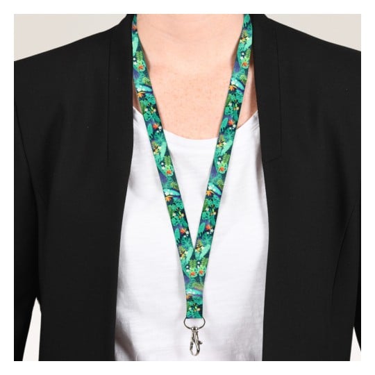 Das Bild zeigt eine Person, die einen schwarzen Blazer über einem weißen Hemd trägt. Sie tragen ein buntes Lanyard mit einem Muster aus Grünpflanzen und Blumen, das an einem Clip befestigt ist.