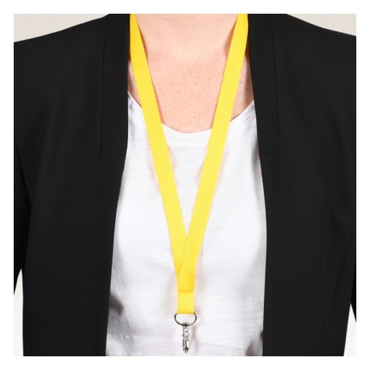 Das Bild zeigt eine Person, die einen schwarzen Blazer über einem weißen Hemd trägt, mit einem leuchtend gelben Schlüsselband, das von ihrem Hals hängt und an dem ein Clip befestigt ist.