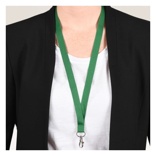 Das Bild zeigt eine Person, die einen schwarzen Blazer über einem weißen Hemd trägt, mit einem grünen Lanyard, das um ihren Hals hängt. Das Lanyard hat unten einen Clip, wahrscheinlich zum Halten eines Ausweises oder Abzeichens.