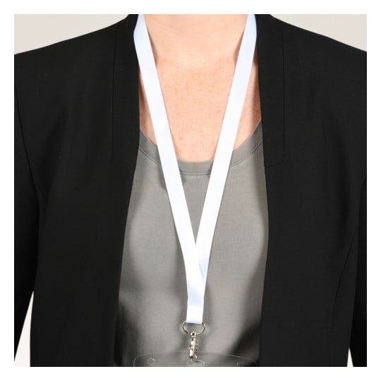 Das Bild zeigt eine Person, die einen schwarzen Blazer über einem grauen Oberteil trägt, mit einem weißen Umhängeband, das um den Hals hängt. Das Umhängeband hält ein transparentes Namensschild oder einen Ausweis.
