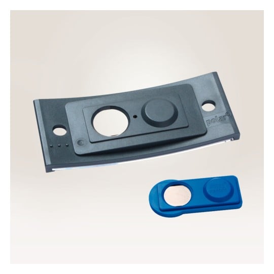 Das Bild zeigt ein schwarzes Gerät mit einem kreisförmigen Ausschnitt und einem Knopf, daneben eine blaue Komponente mit einem kreisförmigen Metallstück. Beide Gegenstände scheinen technikbezogen zu sein.