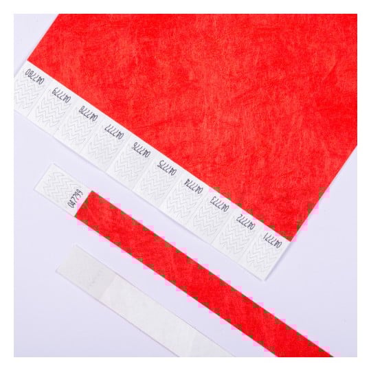 Das Bild zeigt ein großes rotes Blatt Papier mit Klebestreifen, die oben angeordnet sind, sowie ein paar zusätzliche Streifen unten, alle mit Zickzackmustern.