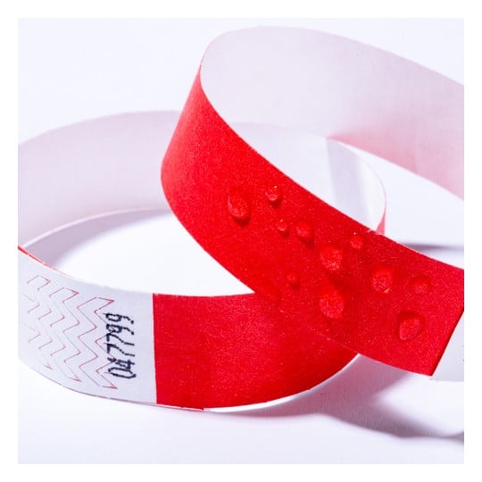 Das Bild zeigt zwei Armbänder, eines in Rot und das andere in einem Mix aus Rot und Weiß mit einem Zickzackmuster. Das rote Armband hat Wassertropfen auf seiner Oberfläche.