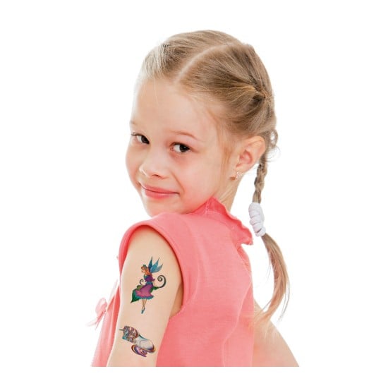 Ein junges Mädchen mit einem verspielten Lächeln, trägt ein pinkes Shirt und zeigt temporäre Tattoos auf ihrem Arm. Ein Tattoo zeigt eine Fee und ein anderes ein Einhorn.