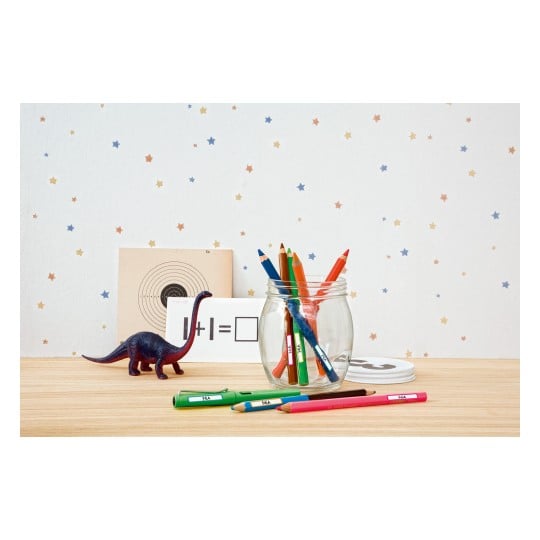 Das Bild zeigt ein Glas gefüllt mit Farbstiften auf einem Holztisch, zusammen mit einem Spielzeug-Dinosaurier, einigen Lernkarten und einem sternförmigen Hintergrund.