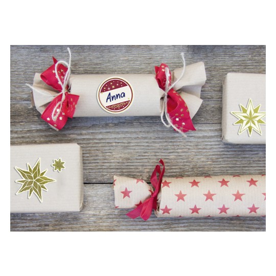 Das Bild zeigt mehrere dekorierte Geschenkpakete, die auf einer Holzfläche angeordnet sind. Die Geschenke sind in Packpapier mit festlichen Bändern und Aufklebern verpackt und vermitteln ein gemütliches, festliches Thema.