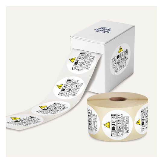 Das Bild zeigt eine Schachtel mit Etiketten, die verschiedene Warnsymbole tragen. Auf der rechten Seite befindet sich eine Rolle von Etiketten und ein teilweise entrolltes Blatt von Etiketten mit Sicherheitsicons.
