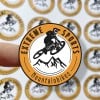 Der Logosticker zeigt ein rundes Logo mit einem springenden Mountainbike-Fahrer.
