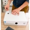 Bedrucktes Versandetikett wird auf weißes Paket aufgebracht.