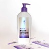 Auf einem Body Lotion Behältnis klebt ein bedruckter Aufkleber aus Perlmutt-Folie. Auf dem Aufkleber steht "aura Body Lotion" und eine Blume ist abgebildet. Neben dem Behälter sieht man die Bögen mit bedruckten Aufklebern.