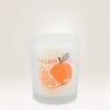 Auf einem Kerzenglas klebt ein Etikett auf dem Seville Orange steht und eine Orange und ein Orangenanschnitt zu sehen sind.