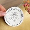Auf einem Baumwoll-Papier-Aufkleber ist ein florales Motiv abgebildet. Er wird auf die Verpackung eines Blumenstraußes geklebt.