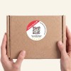 Hand hält ein paket mit rundem Sticker.