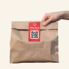 Hand hält eine Food Tüte mit QR Code Sticker.