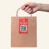 Hand hält eine Tüte mit QR-Code Sticker.