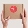 Hand hält Paket mit rundem Sticker.