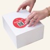 Hand klebt Danke-Sticker auf.