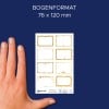 Das Bild zeigt eine Hand neben einem Blatt dekorativer Aufkleber mit goldenen Rahmen. Das Blatt misst 76 x 120 mm und zeigt verschiedene einzigartige Designs in Gold, die vor einem marineblauen Hintergrund gesetzt sind.