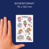 Das Bild zeigt eine Hand, die ein Blatt mit temporären Tattoos hält, das bunte Feenfiguren und Einhörner vor einem blauen Hintergrund darstellt. Die Abmessungen des Tattoo-Blattes sind 76 x 120 mm.