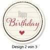 Das Bild zeigt ein kreisförmiges Design mit den Worten 'Happy Birthday' in stilisierten Schriftarten. Ein kleines Herz ist in das Design integriert, und es hat einen dekorativen Rand, was darauf hindeutet, dass es sich um einen festlichen Geburtstagsgruß handelt.