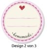 Das Bild zeigt ein rundes Etikett mit einem hellvioletten, gewellten Rand. Es hat ein einfaches beiges Zentrum mit drei leeren Linien zum Beschriften und ein kleines rotes Herz oben. Das Wort 'homemade' ist unten in Schreibschrift geschrieben. Das Design ist als 'Design 2 von 3' bezeichnet.