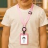 Ein junges Kind trägt ein rosa Lanyard mit einem angehängten ID-Ausweis, der einen Namen und Zoneninformationen zeigt. Der Hintergrund zeigt eine Klassenzimmerszene.