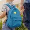 Ein Kind hält ein Buch und geht Hand in Hand mit einem Erwachsenen. Das Kind hat einen blauen Rucksack mit einer gelben Cartoonfigur darauf.