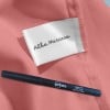Das Bild zeigt einen rosa Stoff mit einem Kleidungsetikett der Marke 'Alba Marceau'. Daneben befindet sich ein Avery Textilstift.