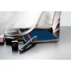Das Bild zeigt eine stilvolle Handtasche, die teilweise geöffnet ist und ein blaues Notizbuch mit einem roten Streifen, einen Stift und einige Kosmetikartikel wie Lippenstift und Nagellack auf einer reflektierenden Oberfläche enthüllt.