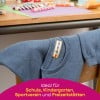 Ein blauer Pullover mit einem Etikett auf einem Stuhl in der Nähe eines Tisches mit bunten Wachsmalstiften und Papierbögen. Das Bild deutet auf Eignung für Schul- und Freizeitaktivitäten hin.