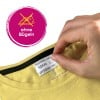 Eine Hand hält ein Bekleidungsetikett in einem gelben Hemd, mit einem Symbol, das Bügeln verbietet, und dem Text 'ohne Bügeln'.