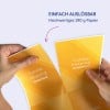 Zwei Hände halten und trennen glänzende gelb-orange Visitenkarten mit der Aufschrift „Coralie Miaping Graphiste“.