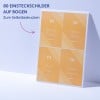 Blatt mit vier orangefarbenen Namenskarten, die an eine blasse Wand gelehnt sind, mit deutschem Text?