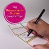 Das Bild zeigt eine Hand, die einen Permanentmarker hält und auf Etiketten schreibt. Es sind bunte rechteckige Etiketten zu sehen, auf denen Text hinzugefügt wird. Der Text 'Mit Permanent-Marker beschriften' erscheint in einer kreisförmigen Grafik am Rand.