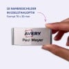 Das Bild zeigt eine Hand, die ein Namensschild von Avery hält. Das Schild trägt den Namen 'Paul Meyer' und ist in Edelstahloptik gestaltet, mit den Maßen 70 x 30 mm.