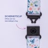 Das Bild zeigt einen Sicherheitsclip, der mit einem bunten Riemen mit Blumenmustern und einem deutschen Text zu seiner Funktion versehen ist.
