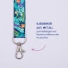 Das Bild zeigt ein buntes Lanyard mit einem Metallclip, ideal zum Befestigen von Namensschildern oder Accessoires. Das Design umfasst tropische Elemente wie Blätter und Vögel. Der Text an der Seite gibt an, wofür es verwendet wird.