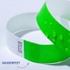 Das Bild zeigt zwei Armbänder, eines in leuchtendem Grün mit Wassertropfen und ein weiteres in Weiß. Das grüne Armband wirkt strukturiert, während das weiße ein Muster aufweist. Der Text 'WASSERFEST' ist zu sehen, was auf wasserdichte Eigenschaften hinweist.