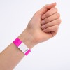 Das Bild zeigt eine Hand mit einem rosa Armband, das einen weißen Abschnitt mit einer Nummer aufweist.