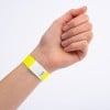 Eine Hand mit einem gelben Armband, das einen weißen Abschnitt und eine darauf gedruckte Zahl hat.