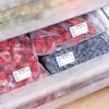 Das Bild zeigt mehrere Packungen gefrorener Beeren, die auf Deutsch etikettiert sind, darunter Erdbeeren und Blaubeeren, die in einem Gefrierschrank gelagert werden.