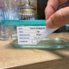 Ein Glasbehälter mit der Aufschrift 'Sauce Bolognese', der Angaben zu den Zutaten, dem Gewicht, dem Hersteller, dem Produktionsdatum und dem Verfallsdatum enthält.